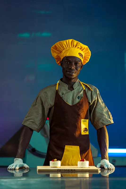 Boulanger de La Baguette d’Or en toque jaune, derrière son plan de travail