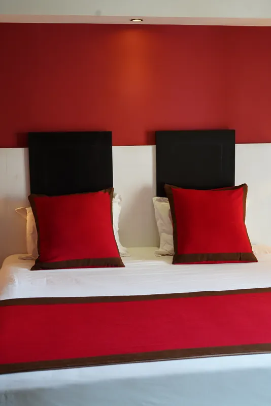 Chambre aux têtes de lit noires et coussins rouges