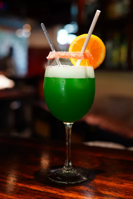 Cocktail vert à l’orange posé sur le comptoir du bar
