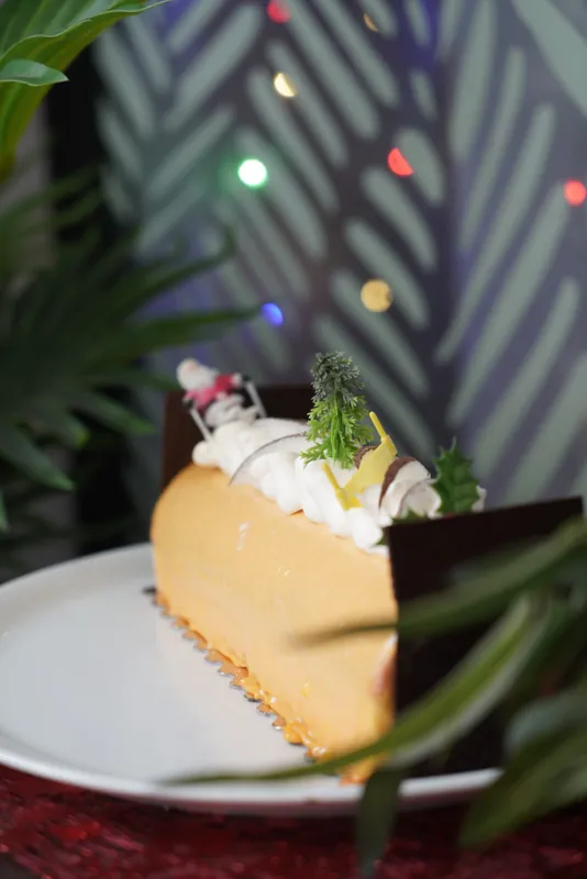 Part de bûche à la mangue, guirlandes lumineuses en arrière-plan