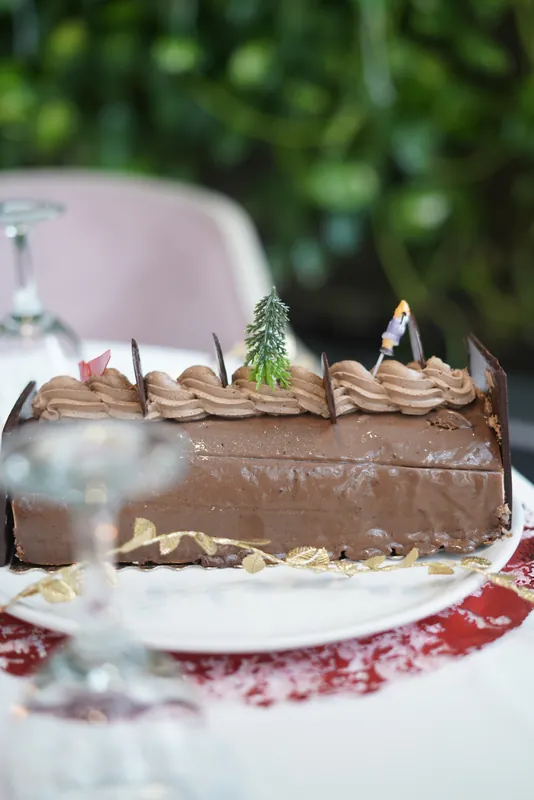 Part de bûche pralinée devant un mur végétal