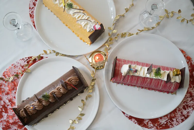Trois bûches de Noël servies sur une table dressée, vue du dessus